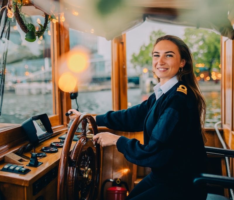 Lachende schipper op salonboot met lichtjes